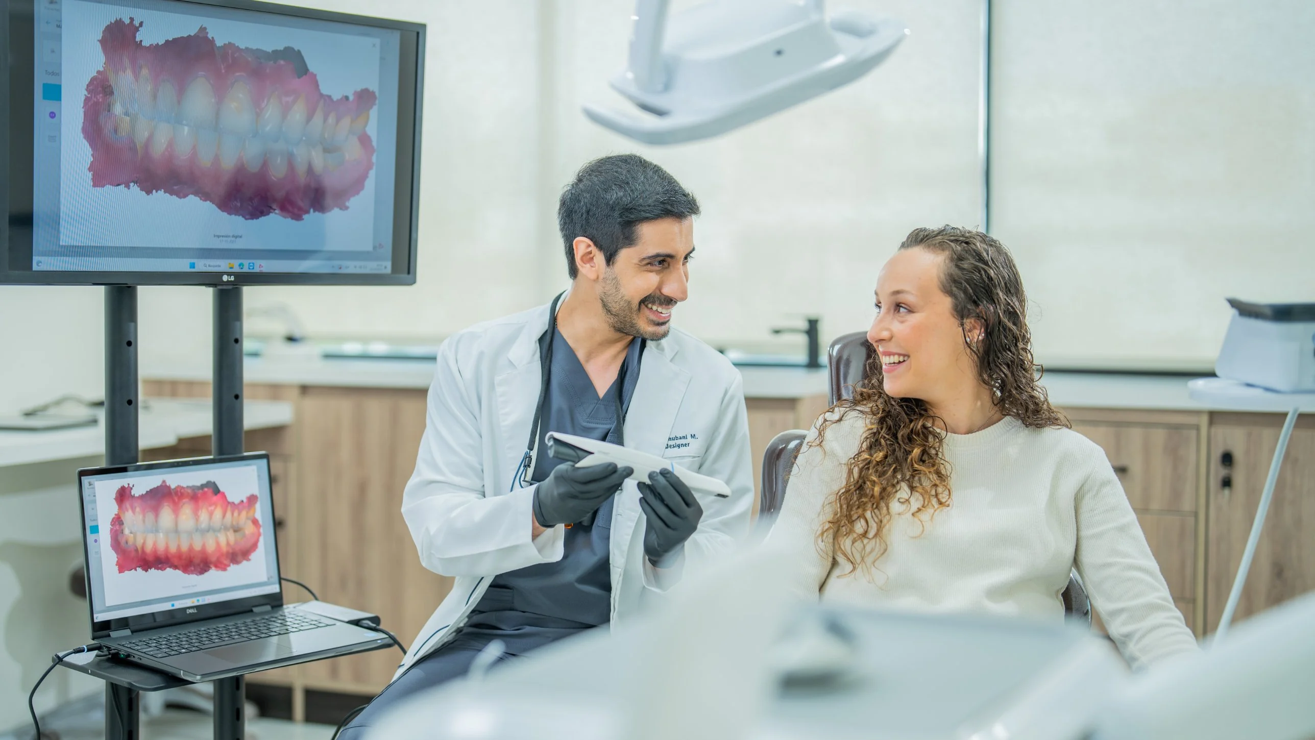 El Dr. Ravi Khubani Mirvani muestra a una paciente su escaneo intraoral 3D en las pantallas del box de Zenclinic Dental